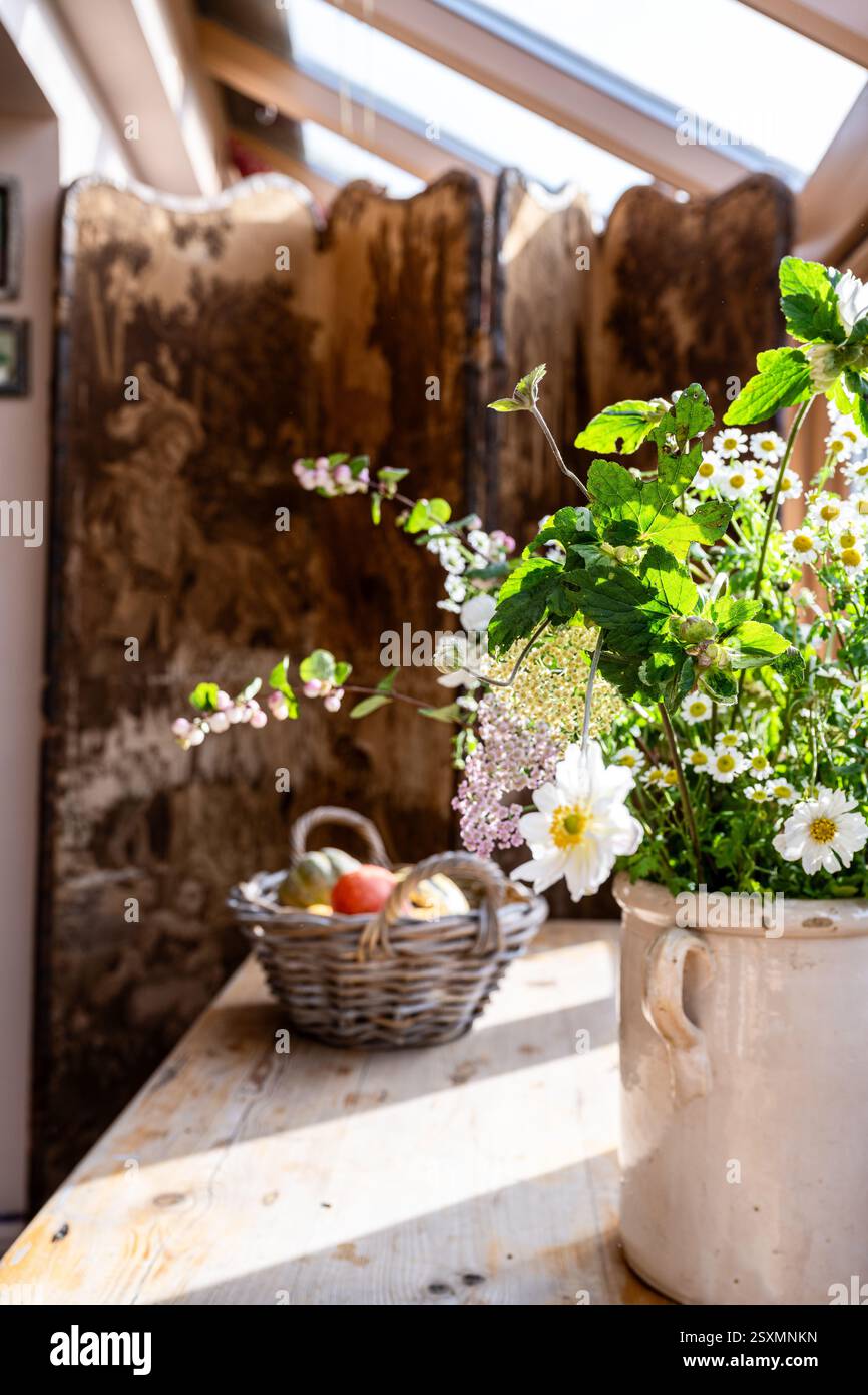 Fleurs sauvages et panier de fruits avec écran pliant dans Chalford tisserands cottage dans les Cotswolds, Gloucestershire, Angleterre, Royaume-Uni. Banque D'Images
