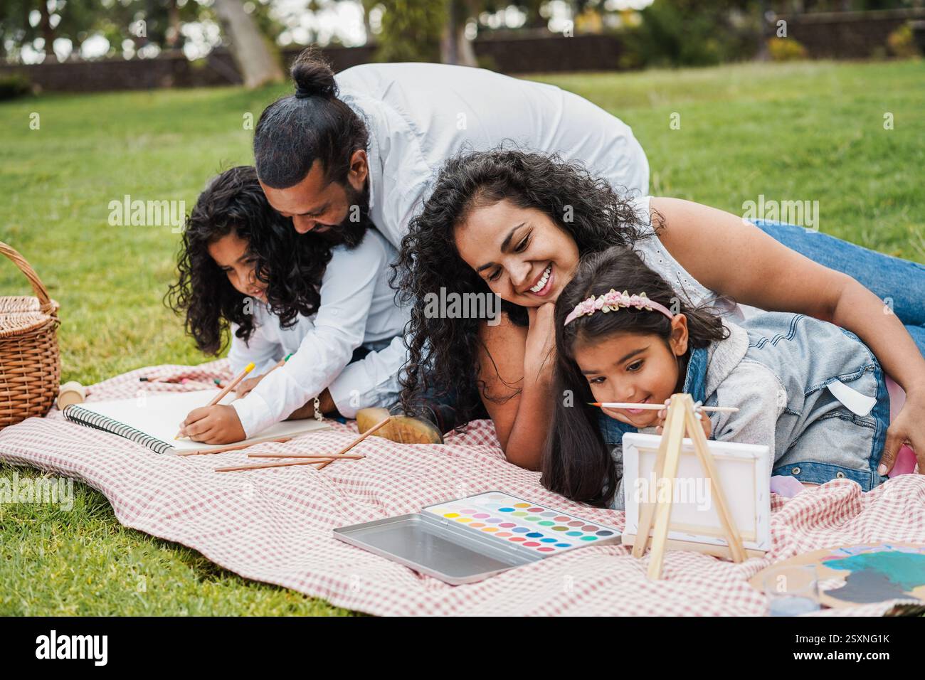 Heureuse famille indienne ayant du plaisir à peindre avec des enfants en plein air au parc de la ville - Spring Time et concept de parentalité - Focus sur le visage de la mère Banque D'Images