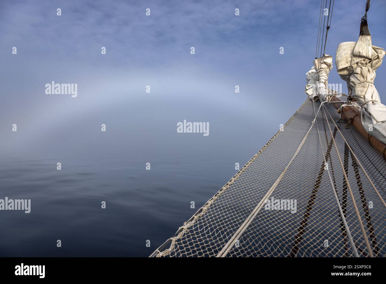 Proue d'un voilier coupant dans le brouillard à Hall Bredning, Scoresby Sund, Groenland. Il y a un arc de brouillard dans le ciel, un phénomène causé par la lueur Banque D'Images