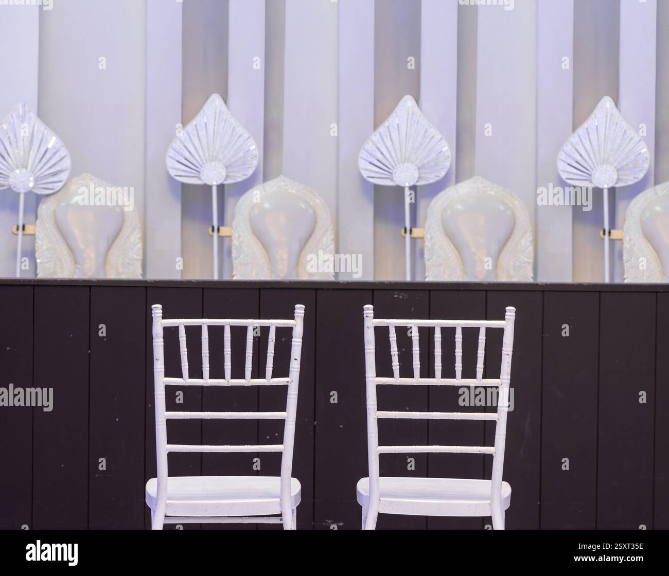 Une paire de chaises blanches sous un podium avec des sièges pour les moines bouddhistes prêts pour un rituel de mariage Banque D'Images