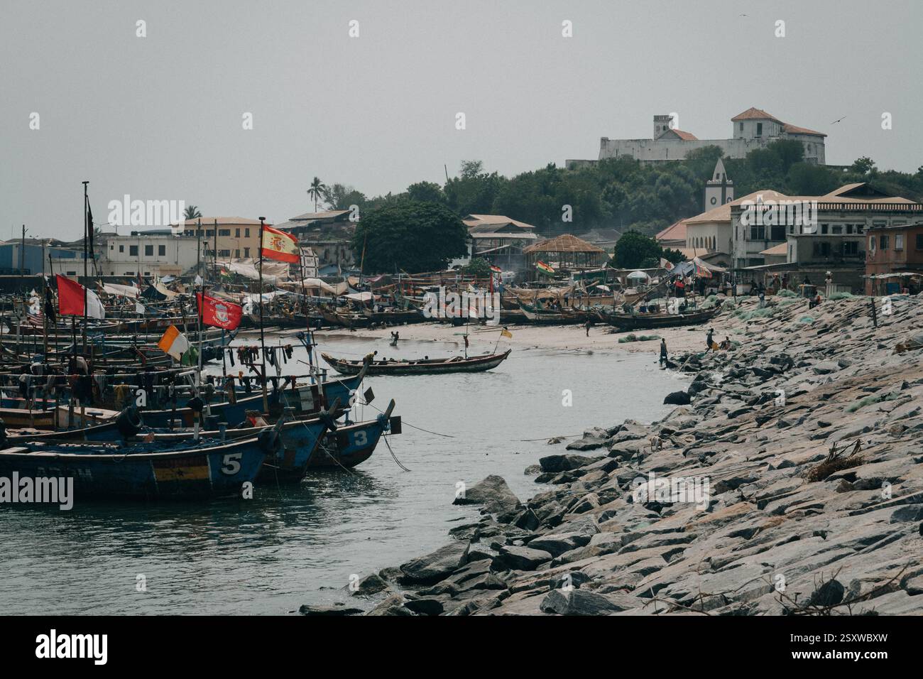 Les bateaux de pêche en bois sur la côte d'Elmina, Ghana, une ville historique d'Afrique de l'Ouest, célèbre pour la communauté de pêcheurs, avec l'ancien fort sur la colline. Banque D'Images