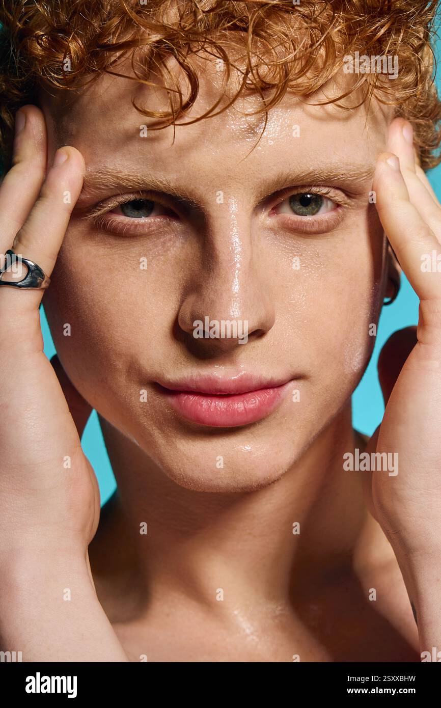 Jeune homme respire la confiance tout en frappant une pose à la mode avec des mains expressives sur son visage. Banque D'Images