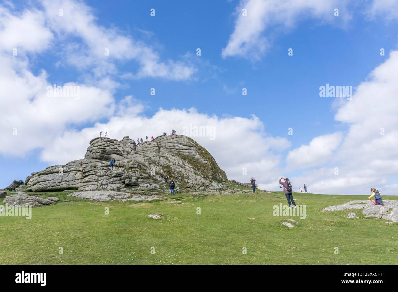 Visiteurs marchant et grimpant sur Haytor Rocks au parc national de Dartmoor dans le Devon, Royaume-Uni. Banque D'Images