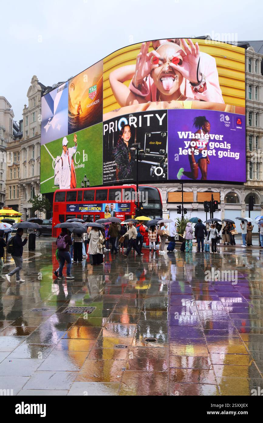 LONDRES, Royaume-Uni - 9 JUILLET 2024 : les gens visitent Piccadilly Circus place emblématique par temps pluvieux à Londres, Royaume-Uni. Banque D'Images