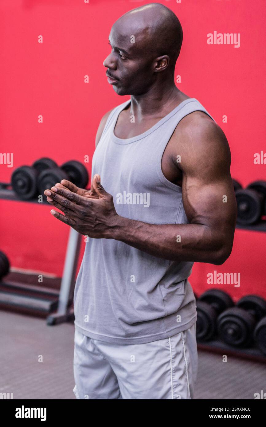 Entraîneur musculaire applaudissant les mains, motivant les étudiants dans la salle de gym avec des haltères Banque D'Images
