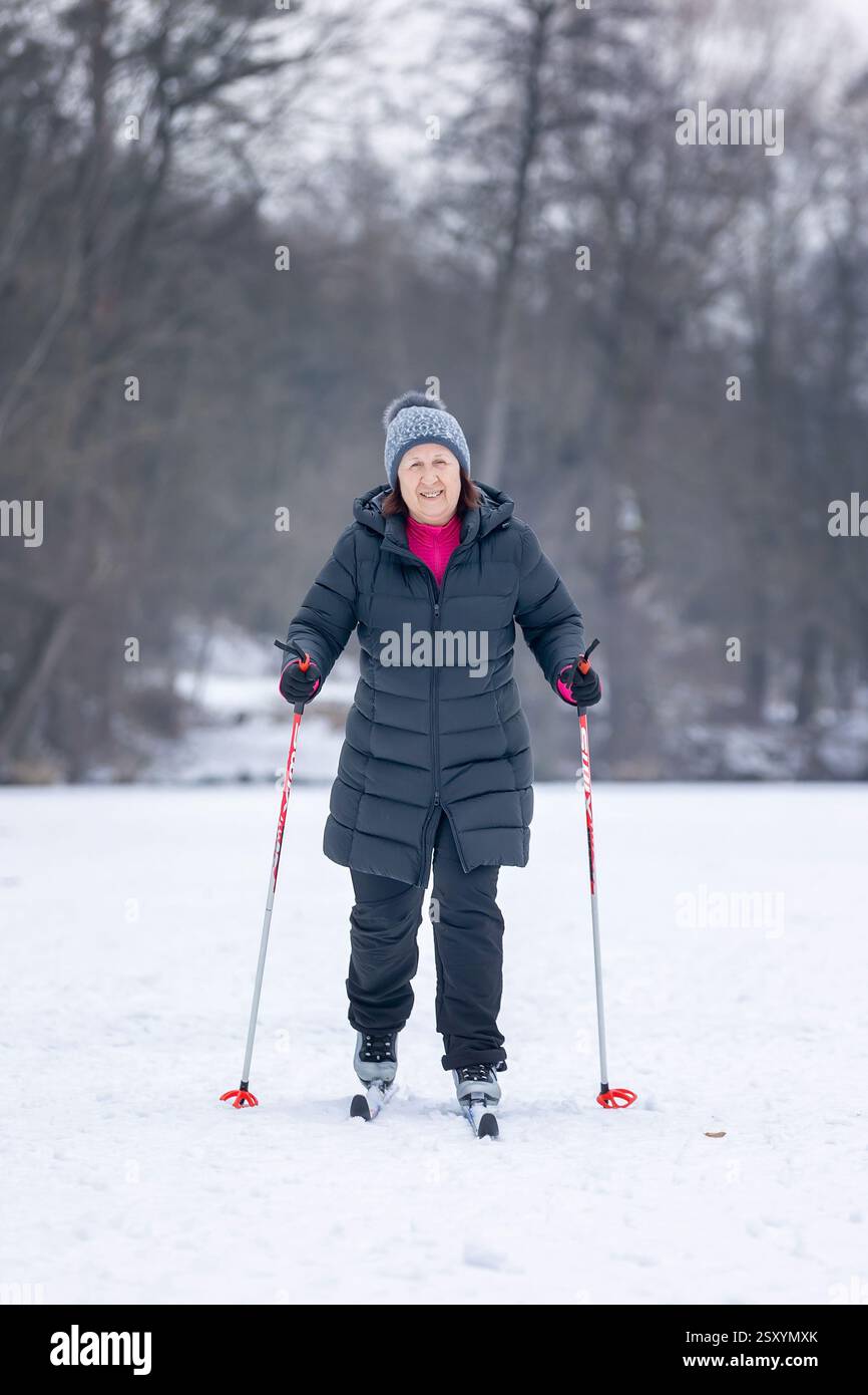 Femme senior dans la neige, ski en courant autour du lac gelé, hiver Banque D'Images