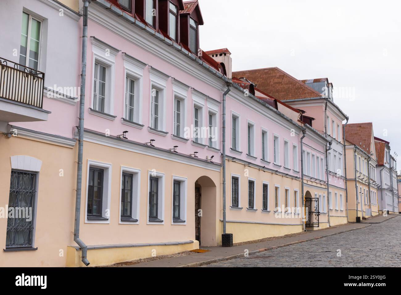 Les charmantes maisons de ville européennes aux couleurs pastel présentent des caractéristiques architecturales traditionnelles, bordant une rue pavée par temps couvert, mettant en valeur le Banque D'Images