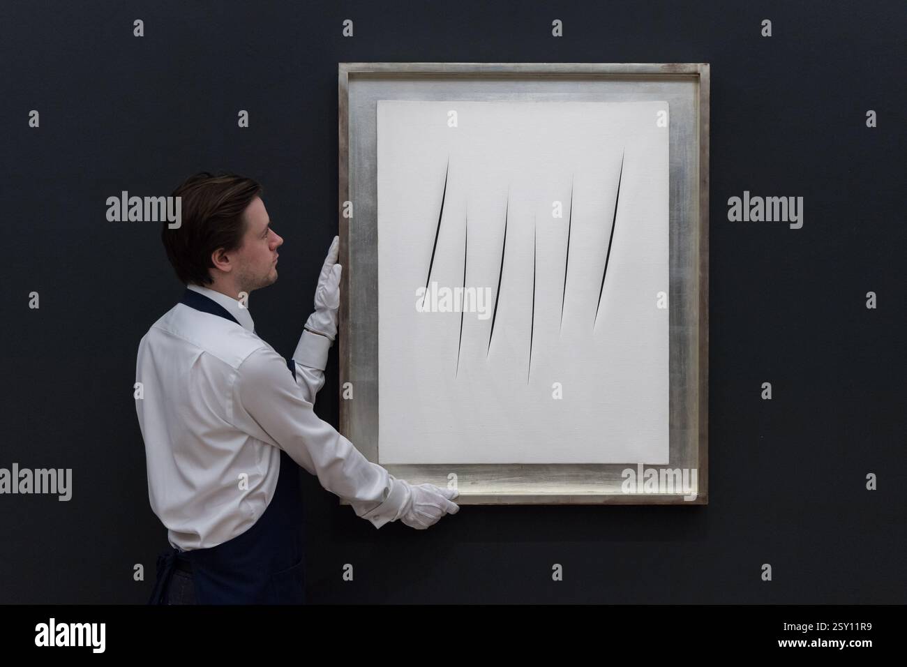 Londres, Royaume-Uni. 26 février 2025. LONDRES, ROYAUME-UNI - 26 FÉVRIER 2025 : un manipulateur d'art tient une peinture de Lucio Fontana "Concetto spaziale, Attese", estimation : £3 200 000 - 5 000 000 lors d'un appel photo à la maison de vente aux enchères Sotheby's présentant les points forts de Modern & Contemporary Art Sales à Londres, Royaume-Uni le 26 février 2025. (Photo de Wiktor Szymanowicz/NurPhoto) crédit : NurPhoto SRL/Alamy Live News Banque D'Images