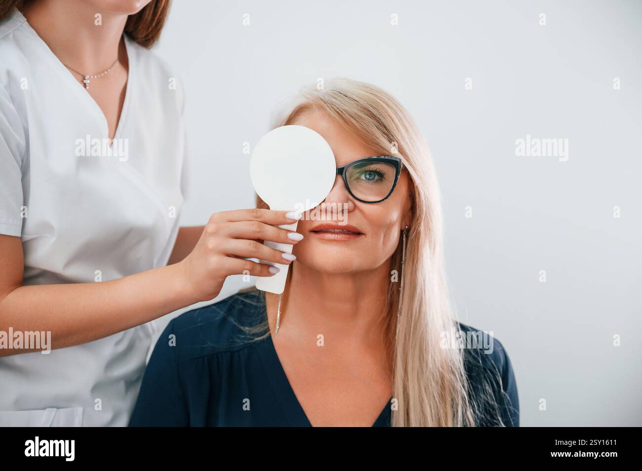 Couvrant l'œil. La vision de la femme est testée par le travailleur de la clinique qui utilise un dispositif spécial. Banque D'Images