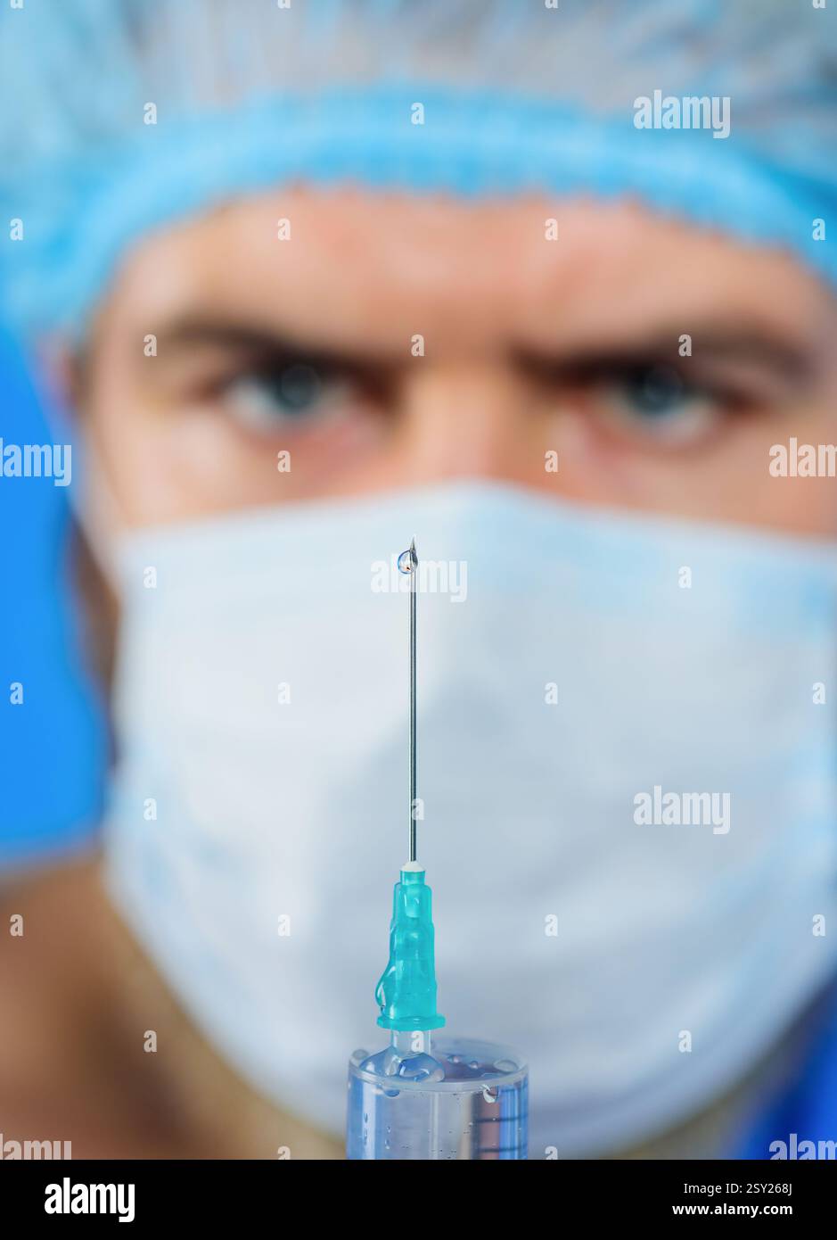 Seringue avec aiguille, gros plan. Médecin masculin dans le masque chirurgical préparant la seringue avec l'aiguille pour l'injection. Vaccination des personnes. Goutte de médicament liquide Banque D'Images