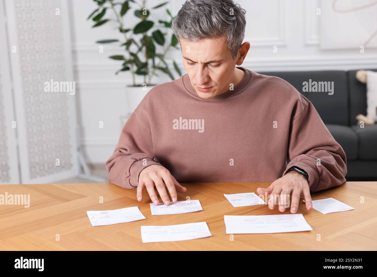 Payer des factures. Homme avec différentes factures à la table en bois Banque D'Images