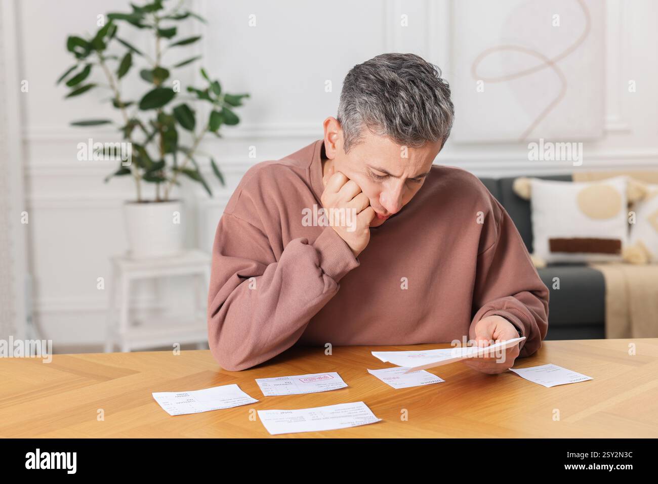 Payer des factures. Homme avec différentes factures à la table en bois Banque D'Images