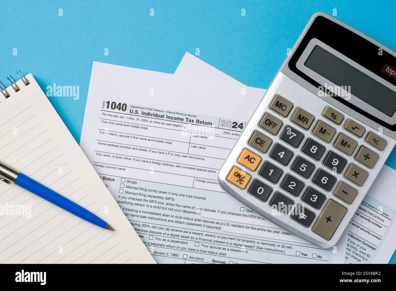 Vue de dessus des formulaires d'impôt, calculatrice et stylo sur la table bleue Banque D'Images