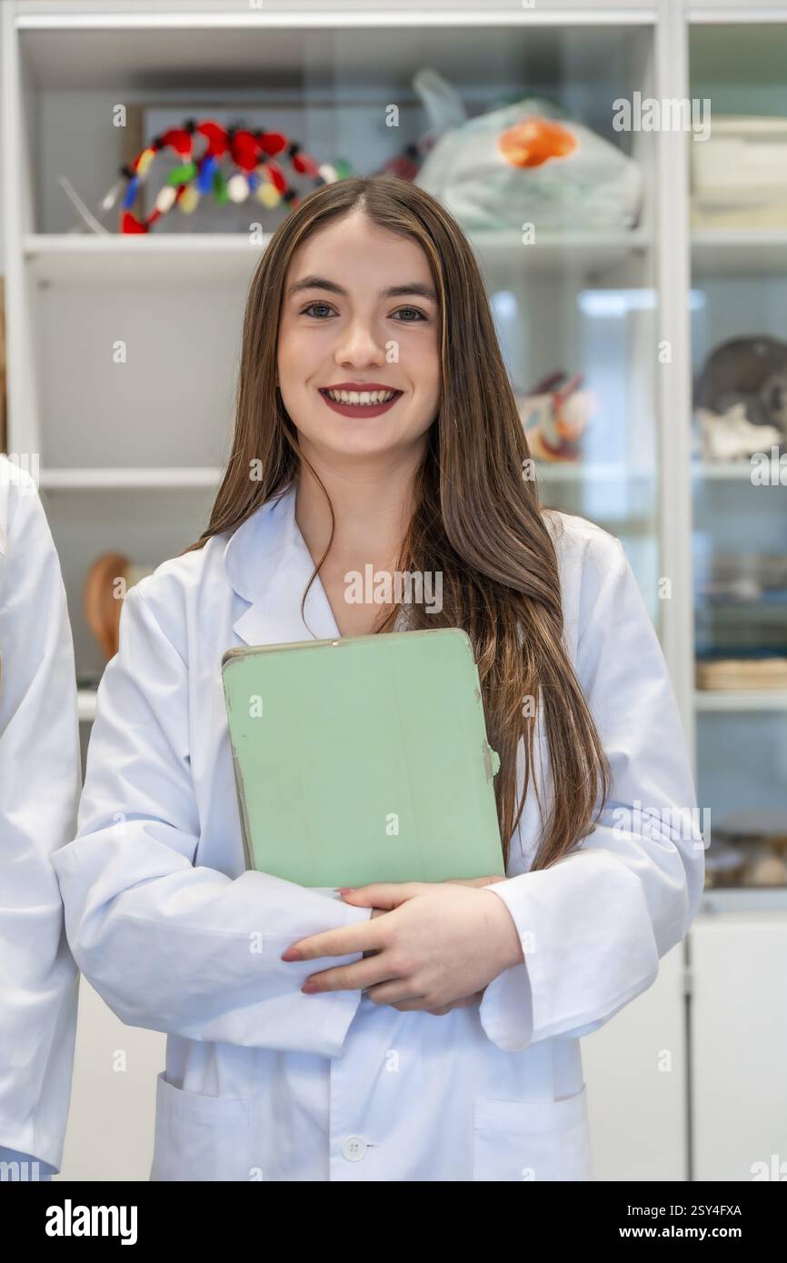 Portrait d’une étudiante en médecine souriante tenant un dossier dans un laboratoire universitaire, mettant en valeur son dévouement à l’éducation en santé Banque D'Images