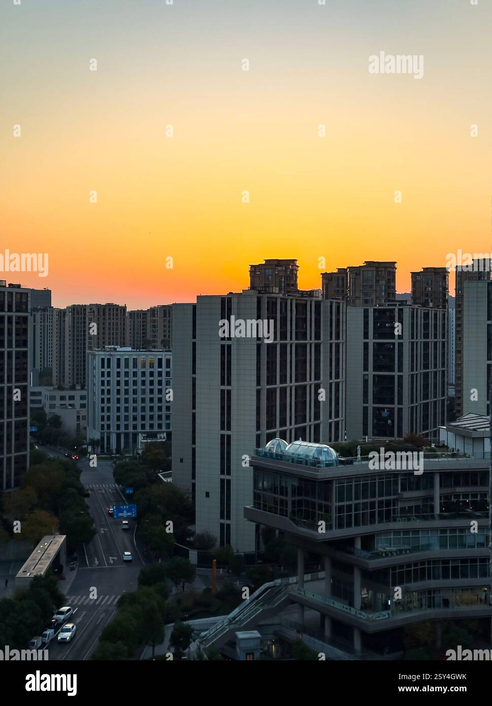 Horizon de la ville pendant le coucher du soleil avec des couleurs vibrantes illuminant les bâtiments et les rues ci-dessous Banque D'Images