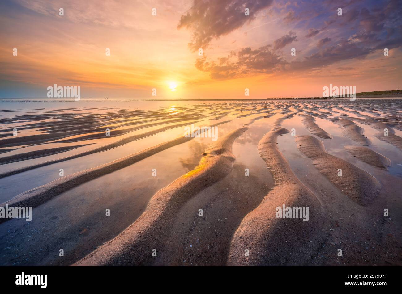 Un coucher de soleil coloré et tranquille sur la plage près de Burgh-Haamstede aux pays-Bas avec des reflets spectaculaires dans le sable humide à marée basse - voyage Banque D'Images