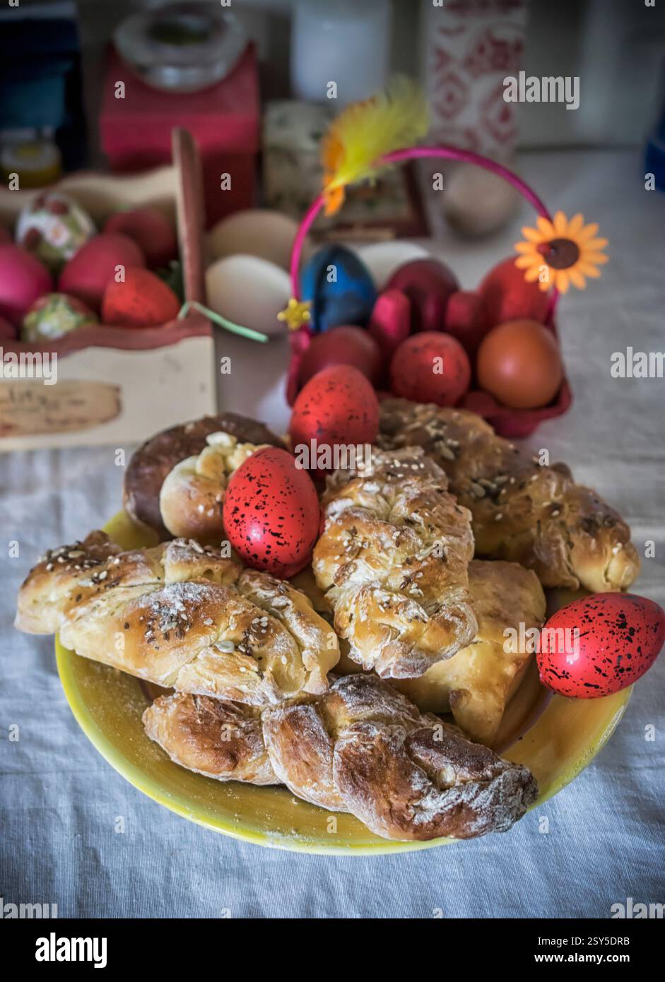 Petits pains de Pâques sucrés sur une assiette et œufs décorés sur une table de fête Banque D'Images