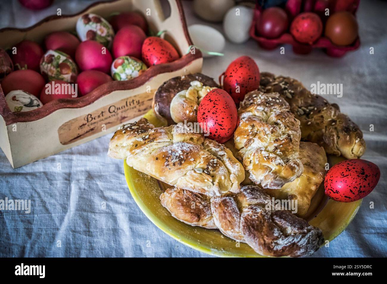 Petits pains de Pâques sucrés sur une assiette et œufs décorés sur une table de fête Banque D'Images