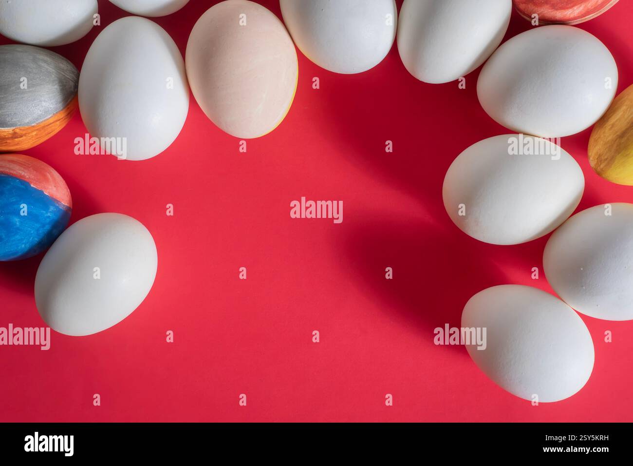 Œufs de Pâques de différentes couleurs, y compris blanc Uni et magnifiquement peint, sont placés sur un fond rouge vif. Banque D'Images
