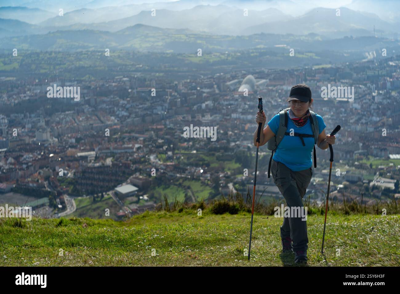 Randonneur avec des bâtons de randonnée grimpant la montagne Naranco, avec la ville d'Oviedo en arrière-plan. Banque D'Images
