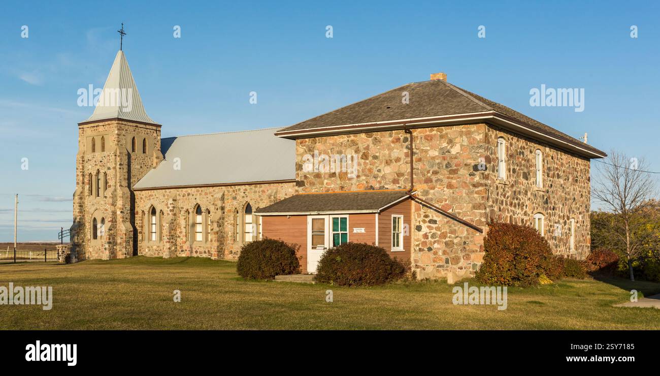 Grand bâtiment en pierre avec un clocher et une petite maison à côté. La maison a un toit blanc Banque D'Images