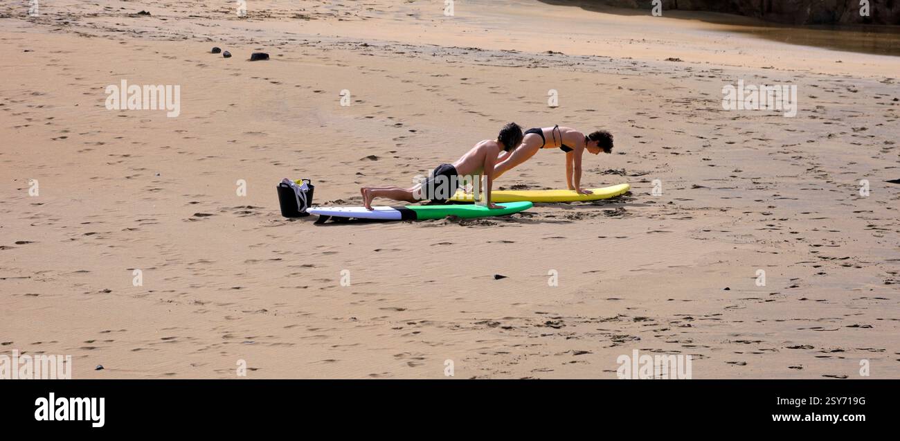Séance de yoga en plein air, deux personnes pratiquent sur des planches de surf sur une plage, Piedra Playa, Fuerteventura, Îles Canaries, Espagne. Prise 2024 Banque D'Images