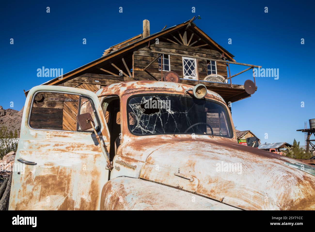 Vieux camion rouillé est garé devant une maison. Le chariot a un pare-brise cassé et un essuie-glace fissuré Banque D'Images Vieux camion rouillé est garé devant une maison. Le chariot a un pare-brise cassé et un essuie-glace fissuré Banque D'Images
