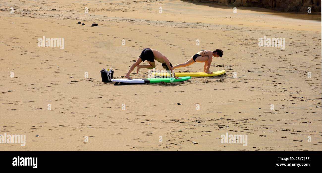 Séance de yoga en plein air, deux personnes pratiquent sur des planches de surf sur une plage, Piedra Playa, Fuerteventura, Îles Canaries, Espagne. Prise 2024 Banque D'Images