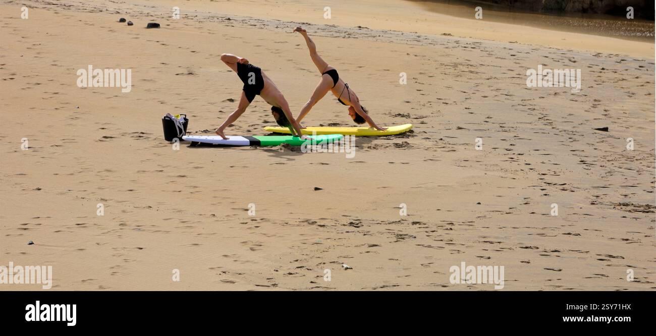 Séance de yoga en plein air, deux personnes pratiquent sur des planches de surf sur une plage, Piedra Playa, Fuerteventura, Îles Canaries, Espagne. Prise 2024 Banque D'Images