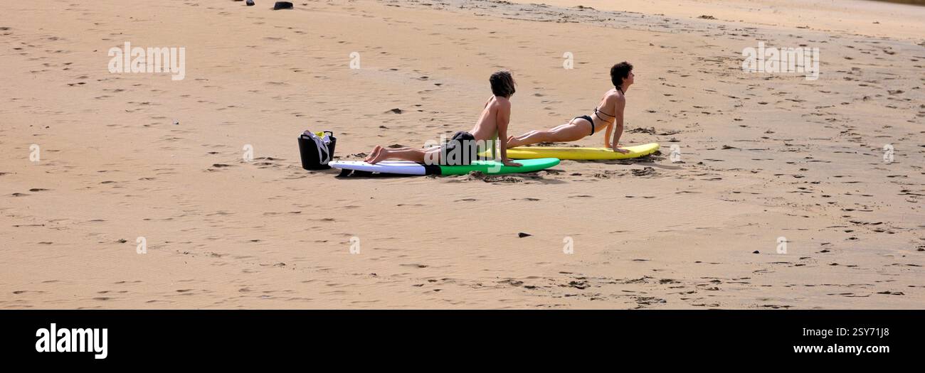 Séance de yoga en plein air, deux personnes pratiquent sur des planches de surf sur une plage, Piedra Playa, Fuerteventura, Îles Canaries, Espagne. Prise 2024 Banque D'Images