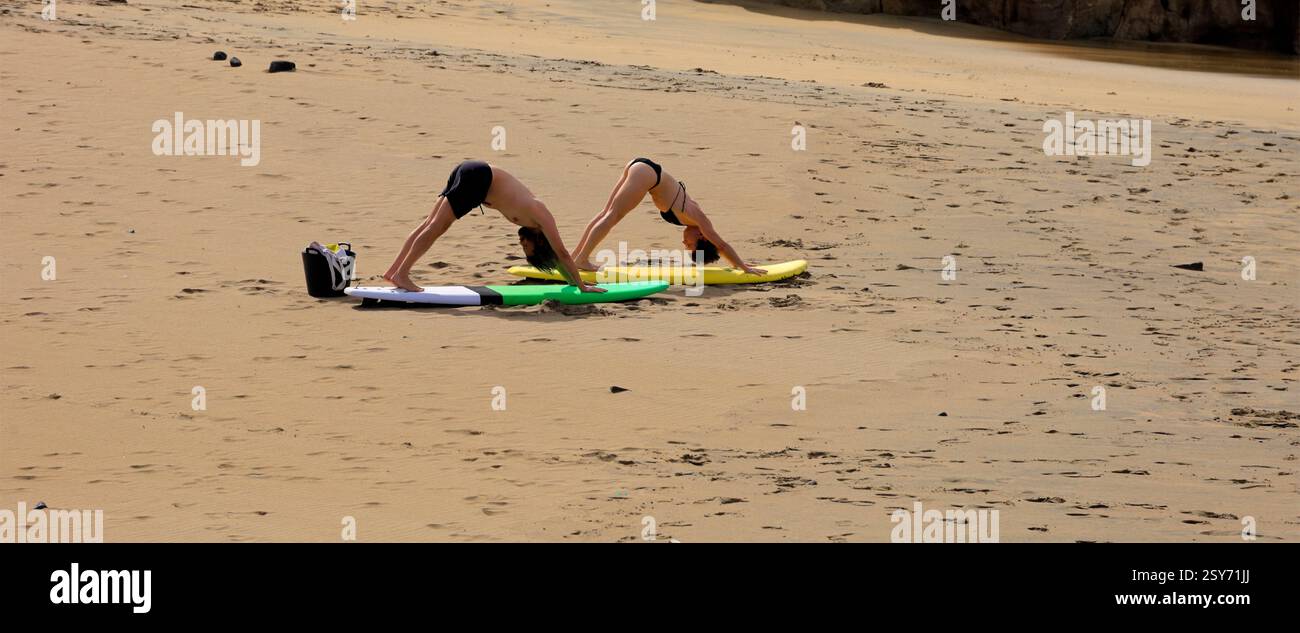 Séance de yoga en plein air, deux personnes pratiquent sur des planches de surf sur une plage, Piedra Playa, Fuerteventura, Îles Canaries, Espagne. Prise 2024 Banque D'Images
