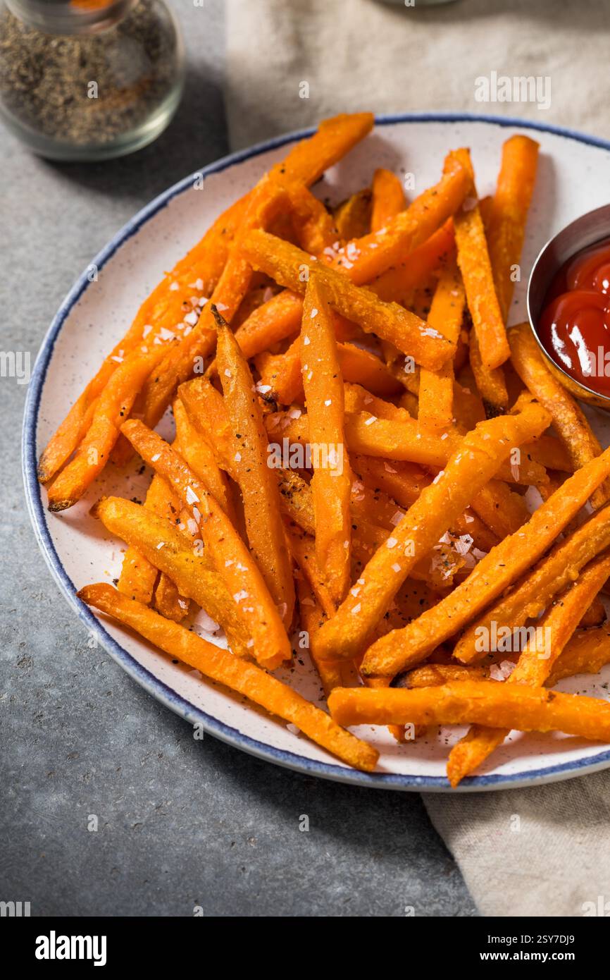 Frites de patate douce à l'orange biologiques avec sel de mer et ketchup Banque D'Images