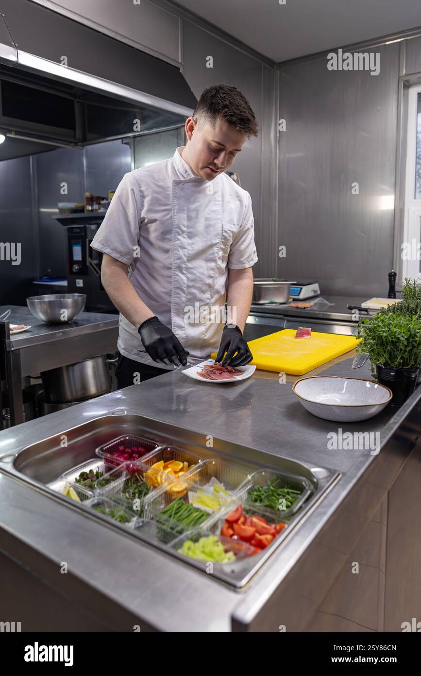 Chef ajoutant du saumon fumé à une salade fraîche dans la cuisine du restaurant Banque D'Images