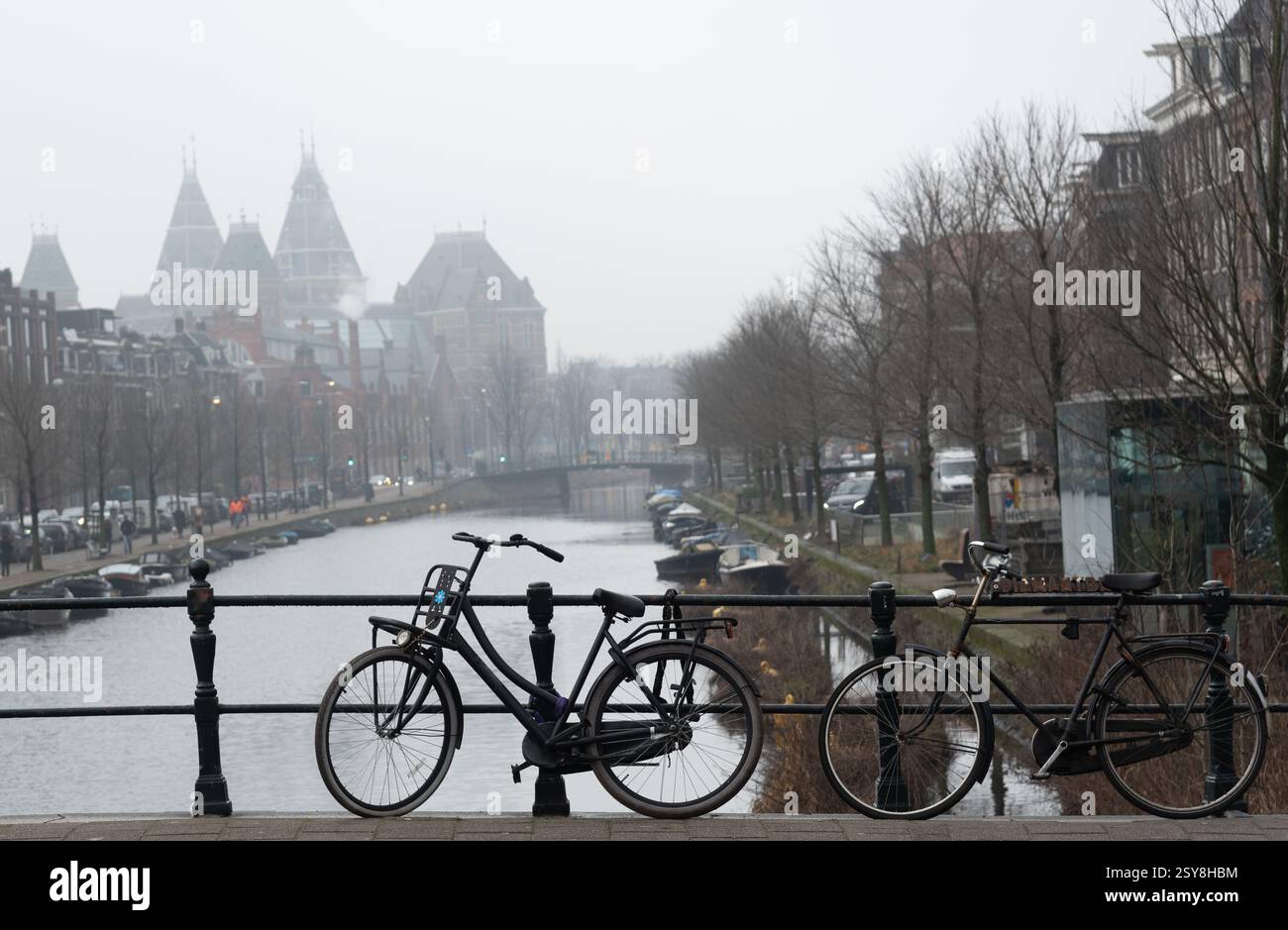 Deux vélos garés sur le pont au-dessus du canal à Amsterdam par jour brumeux. Banque D'Images