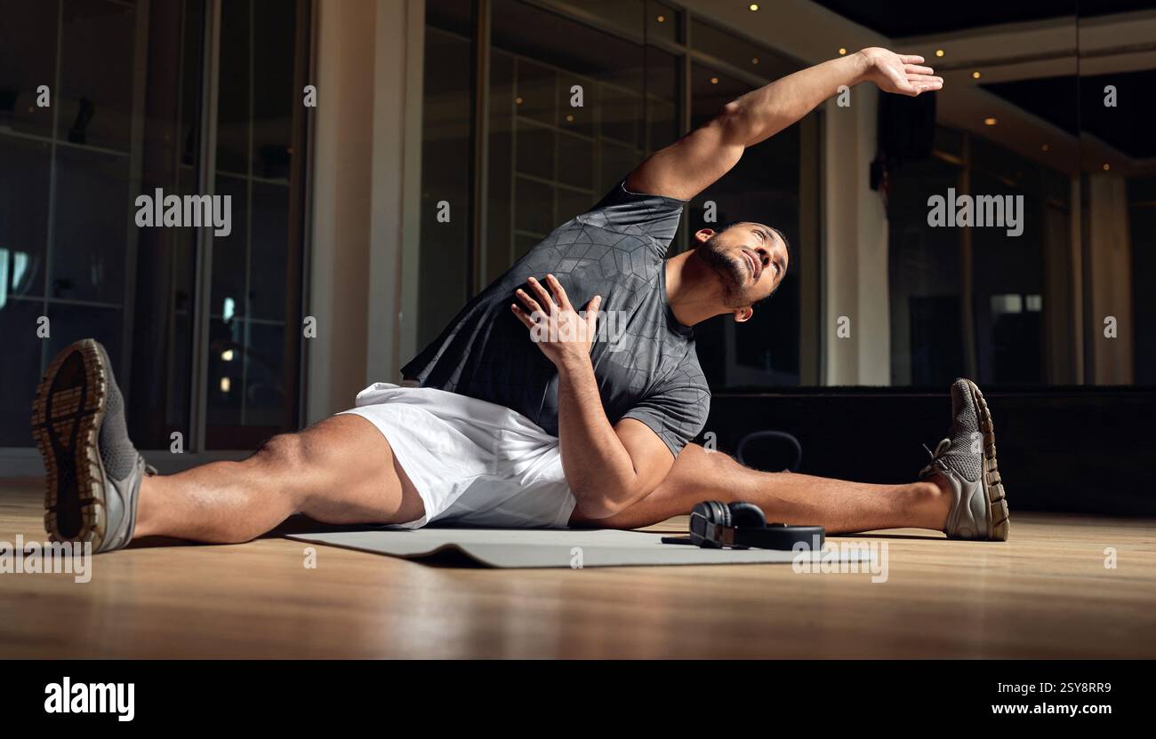 Fitness, bras et étirement de l'homme pour la santé, le bien-être du corps et la préparation de l'entraînement sur le sol de la salle de gym. Échauffez vos muscles, votre souplesse et votre exercice pour commencer Banque D'Images