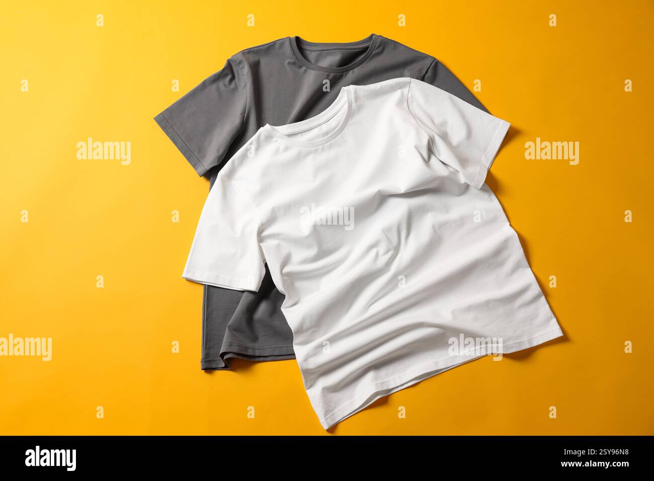 T-shirts vierges sur fond jaune, pose à plat. Maquette pour le design Banque D'Images T-shirts vierges sur fond jaune, pose à plat. Maquette pour le design Banque D'Images