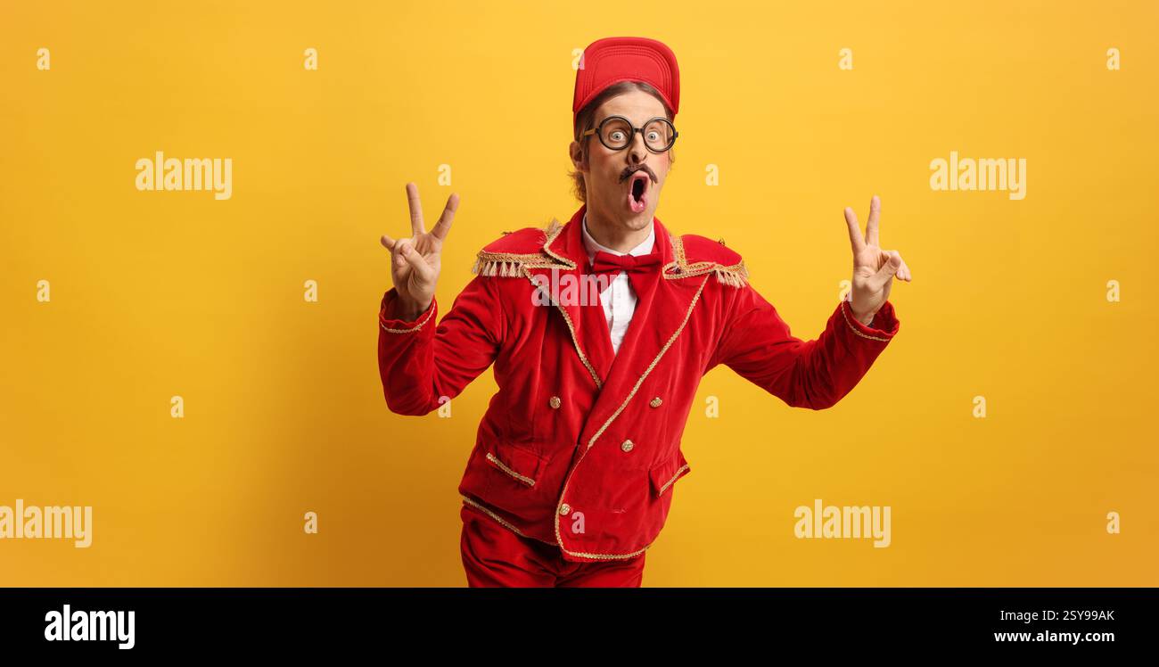 Animateur dans un costume rouge gestuel signe de paix sur un fond jaune Banque D'Images