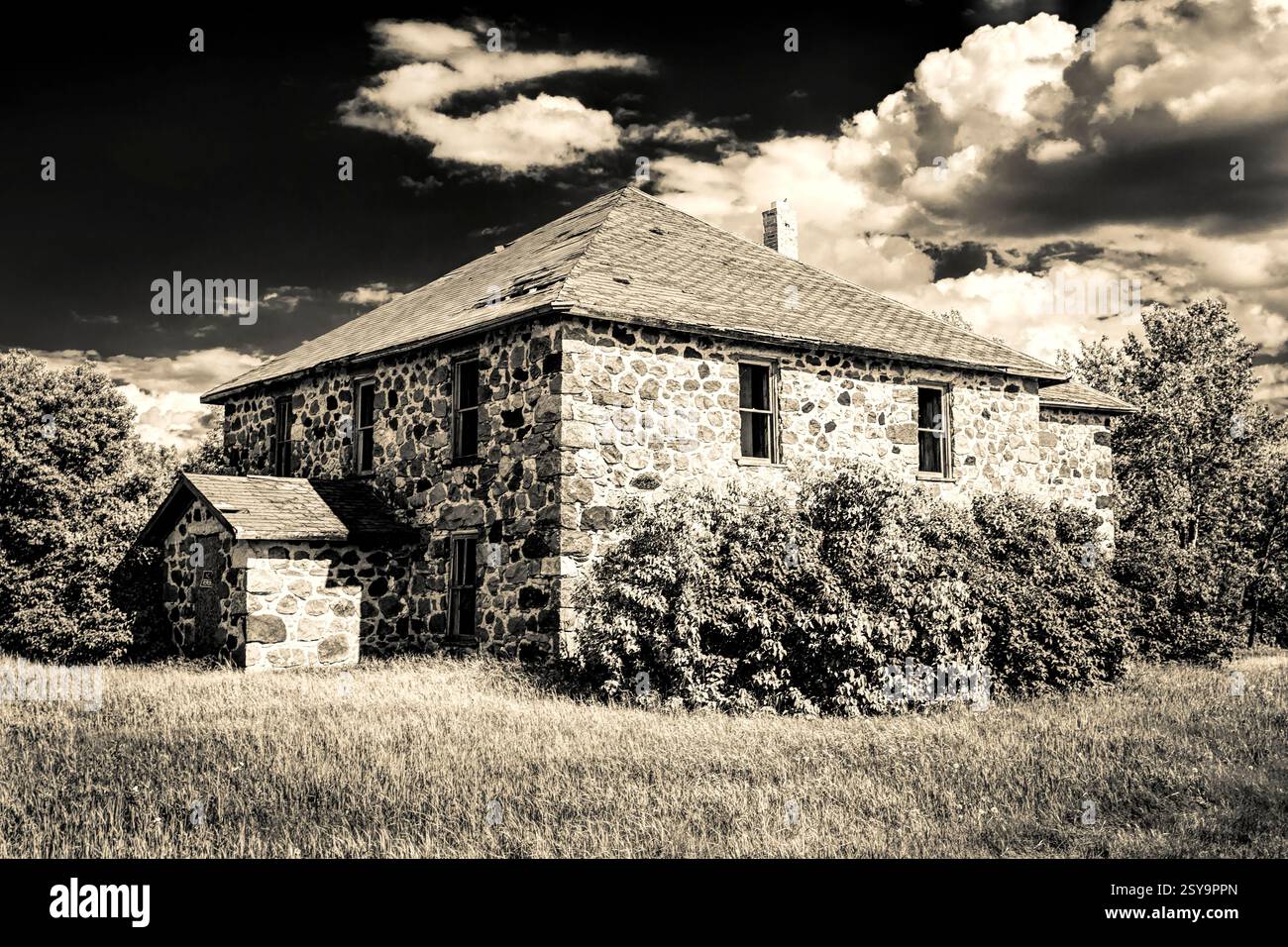 Grande maison en pierre avec un petit hangar devant elle. La maison est entourée par beaucoup d'herbe Banque D'Images