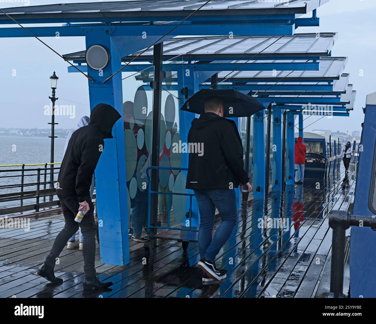 Un homme avec un parapluie à la gare de Pier Head sur le plus long quai de plaisance du monde. Une journée humide à Southend on Sea, ville de Southend. ROYAUME-UNI Banque D'Images