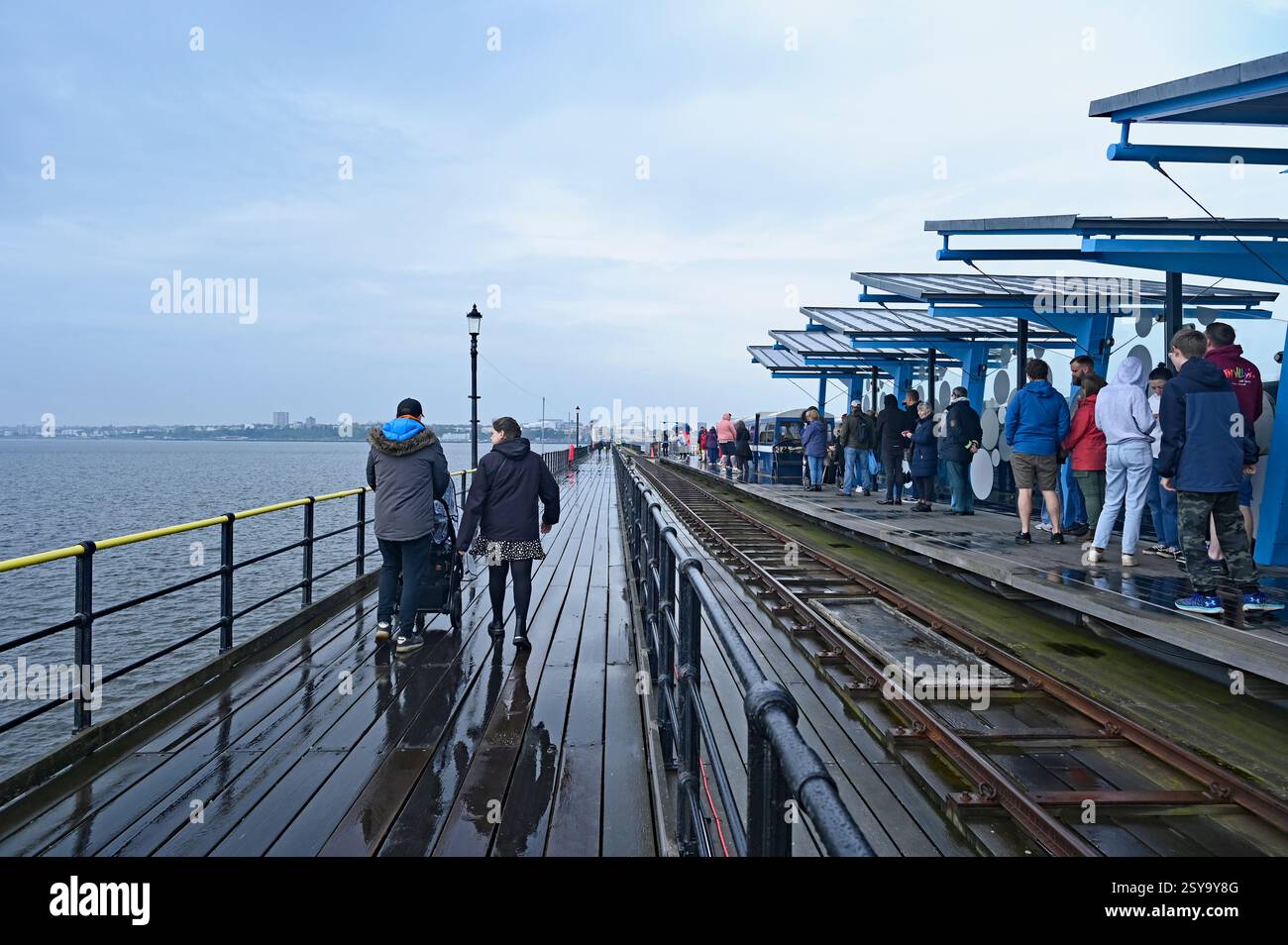 Un couple marche un long chemin de la promenade à la rive sur la plus longue jetée de plaisir dans le monde. D'autres attendent à la gare le train de Southend. ROYAUME-UNI Banque D'Images