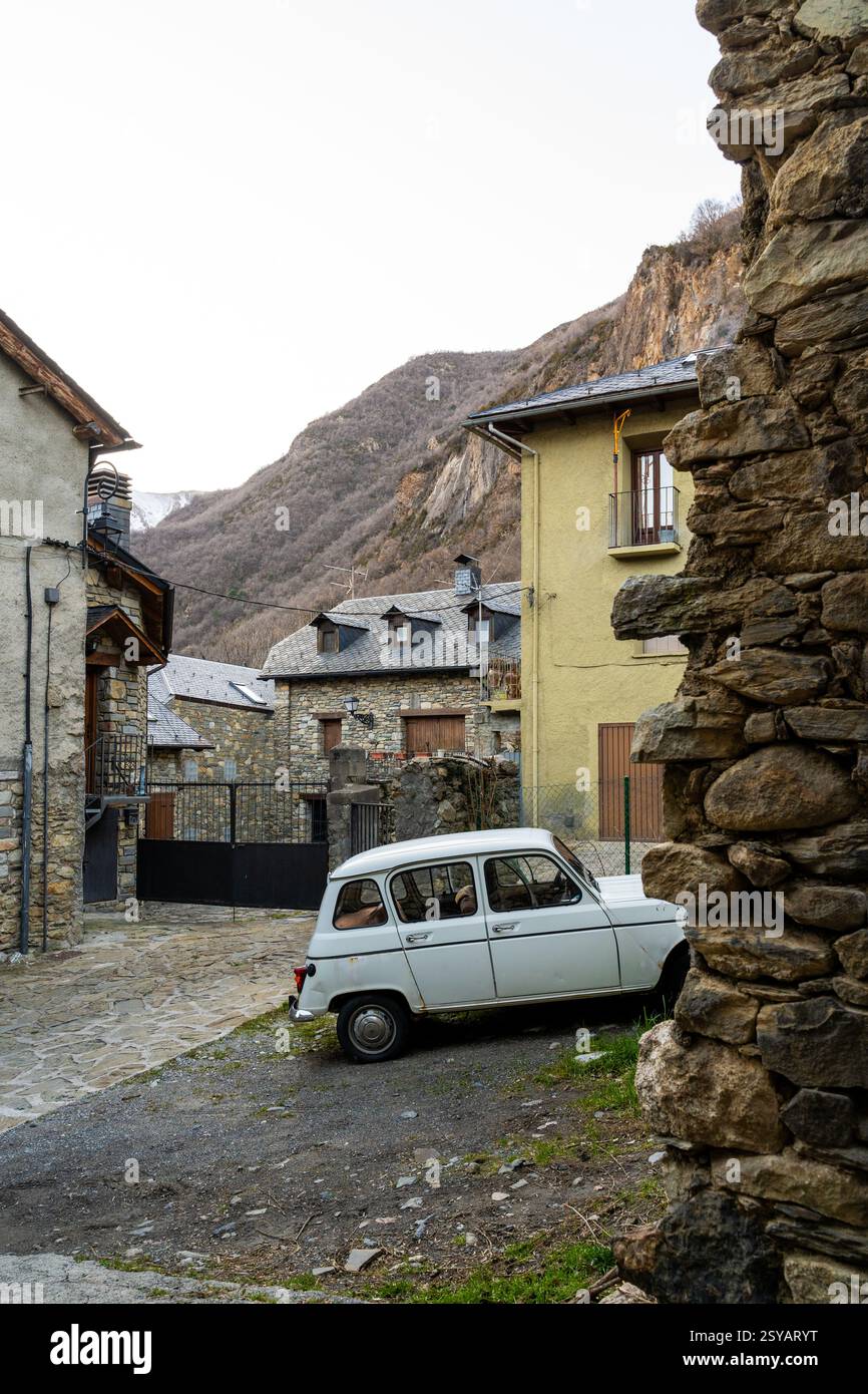 Une scène nostalgique capture une voiture d'époque garée sur une rue pavée dans un village rural paisible, entouré de maisons traditionnelles en pierre contre un Banque D'Images
