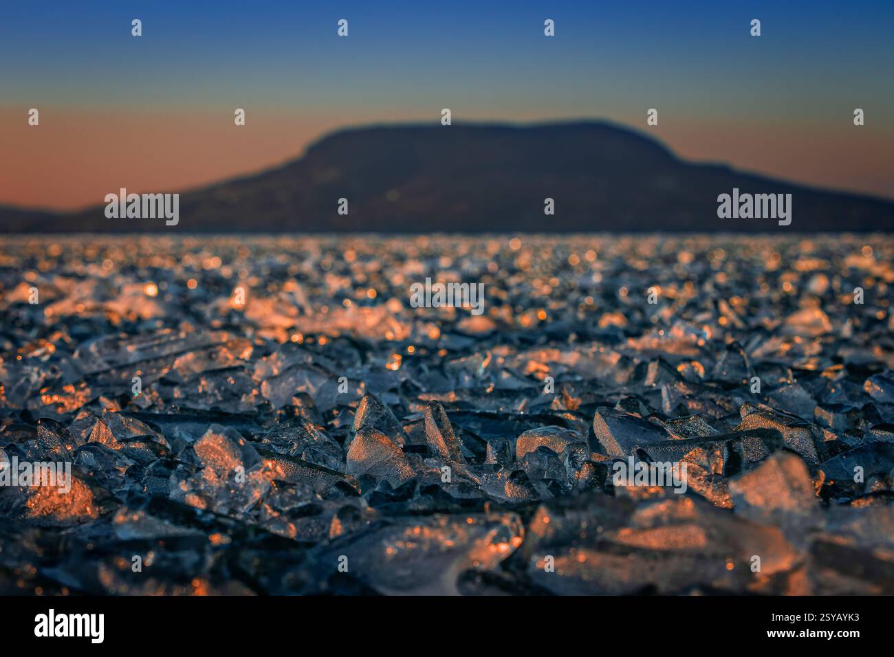 Fonyod, Hongrie - vue panoramique sur le lac Balaton gelé par un après-midi froid d'hiver avec des lumières dorées de coucher de soleil et la montagne Badacsony en arrière-plan Banque D'Images