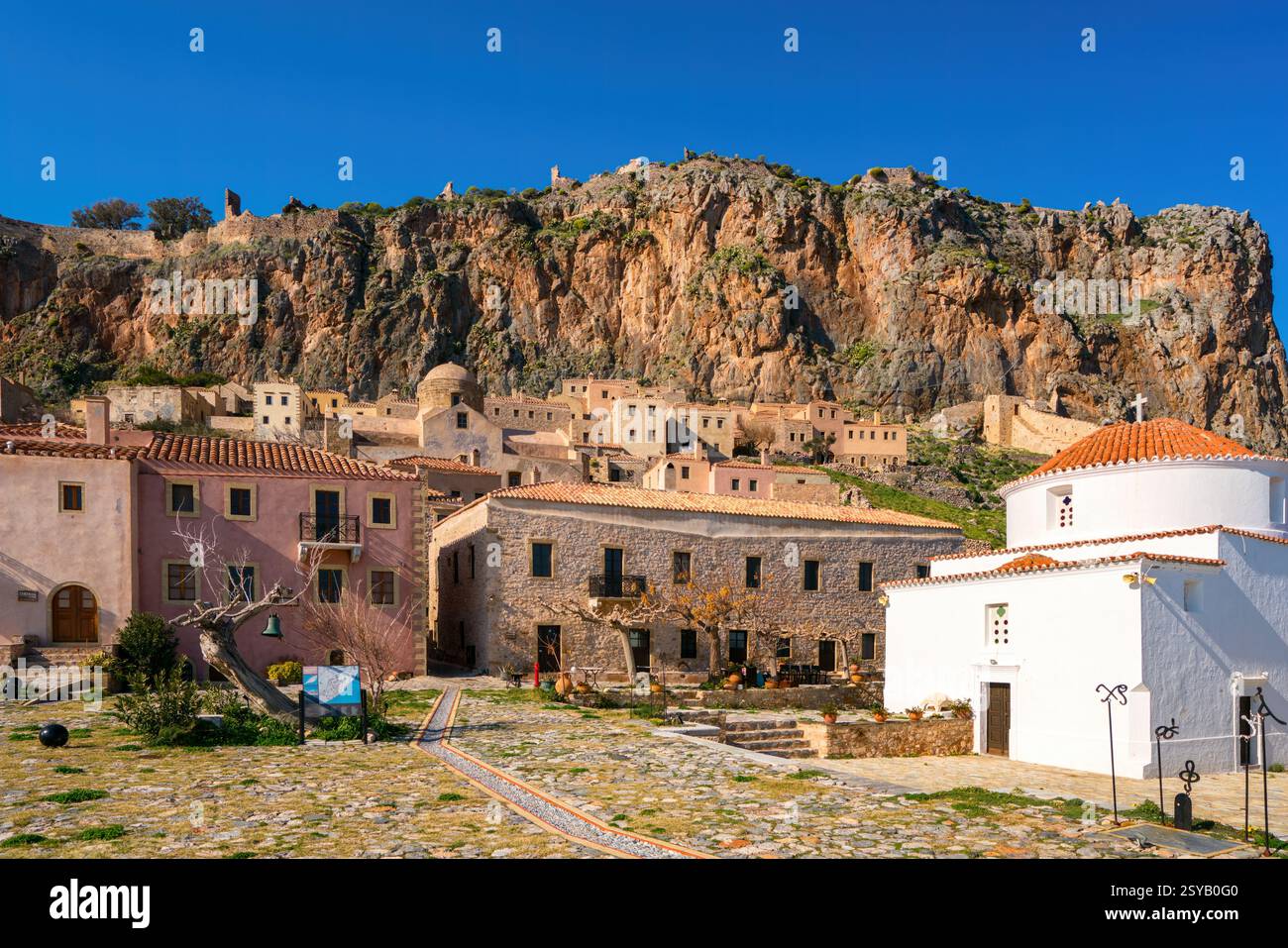 Maisons traditionnelles en pierre et une église orthodoxe à Chryssafitissa Square, Monemvasia, Grèce. Situé contre une falaise rocheuse spectaculaire, cette ville médiévale e Banque D'Images