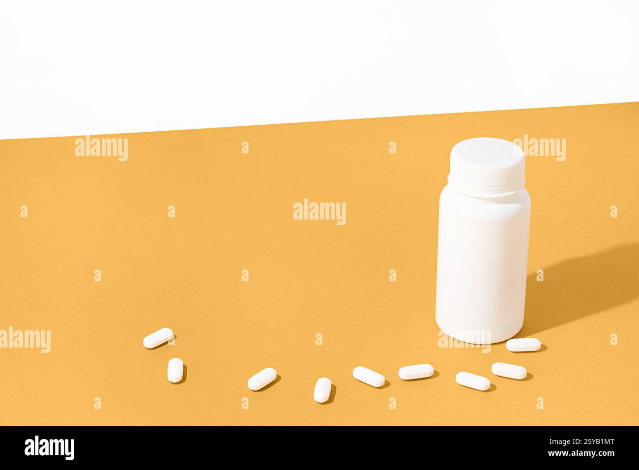 Composition minimaliste avec une bouteille de pilules blanche et des pilules dispersées sur une surface jaune vif. Imagerie idéale pour les produits pharmaceutiques ou de santé Banque D'Images