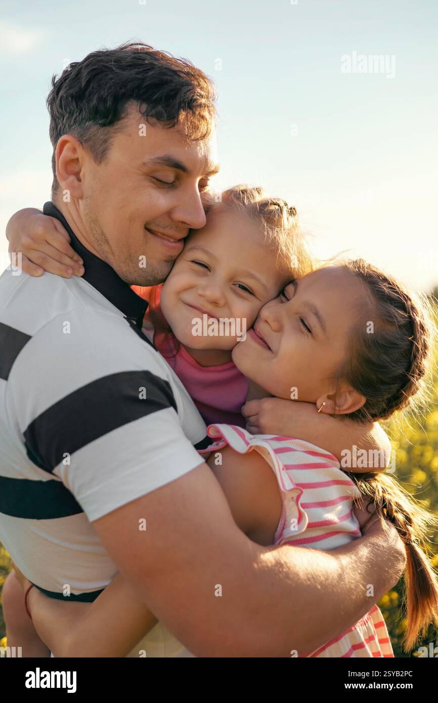 Un jeune père et deux filles s'amusent ensemble à l'extérieur en été. Parentalité heureuse et enfance Banque D'Images