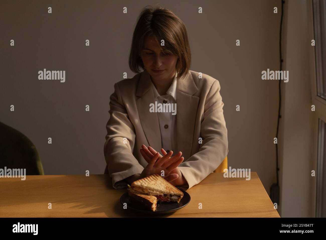 femme pousse une assiette de sandwichs loin d'elle, refus de manger, régime alimentaire, perte de poids, trouble alimentaire Banque D'Images