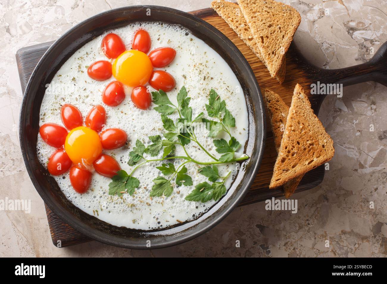 Idée de petit déjeuner en forme de fleur cuisiné œufs frits, persil et tomates cerises en gros plan dans une assiette sur la table. Vue horizontale de dessus Banque D'Images