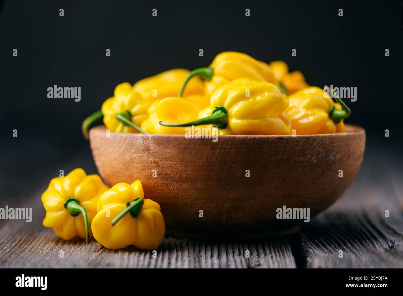 Assiette en bois remplie de poivrons habanero jaunes mûrs (capsicum chinense) sur table en bois rustique. Poivrons mexicains très chauds Banque D'Images