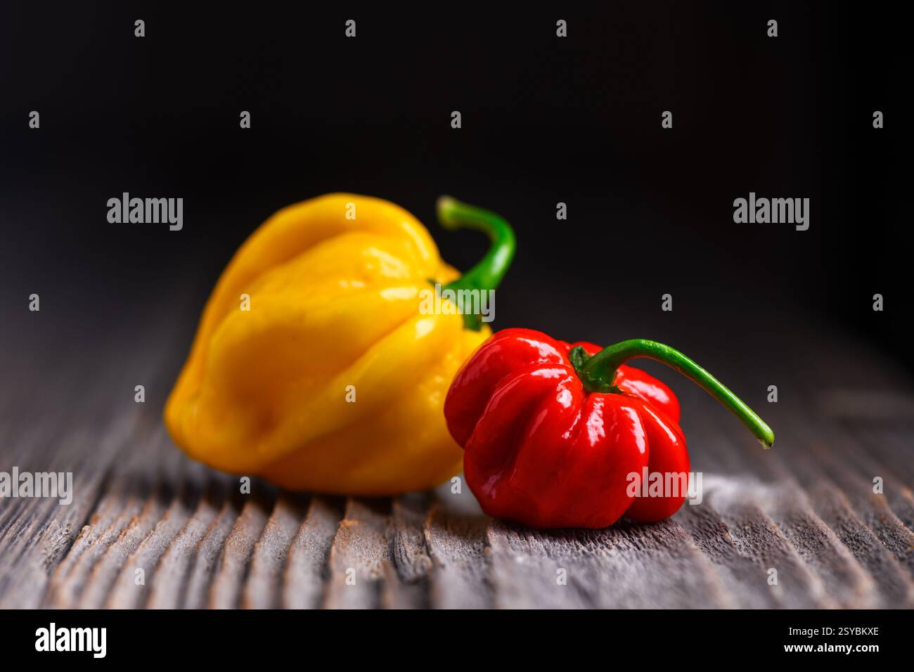 Poivrons habanero rouge et jaune frais (capsicum chinense) sur fond sombre. Poivrons mexicains très chauds sur la table en bois rustique de près Banque D'Images