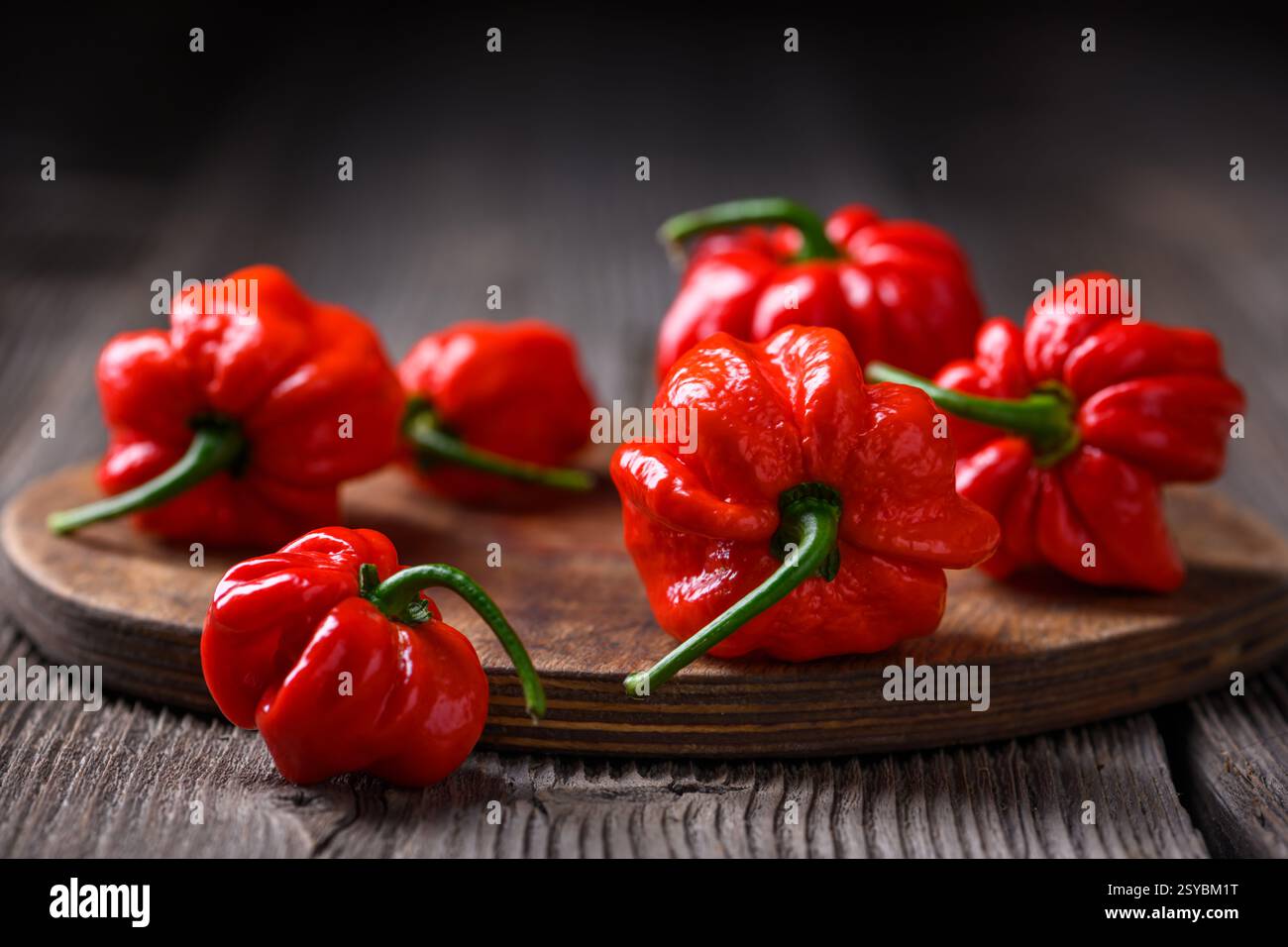 Poivrons habanero rouges frais (capsicum chinense) sur planche à découper en bois sur table rustique. Les poivrons mexicains très chauds se rapprochent Banque D'Images